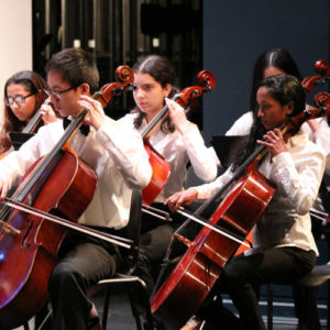 Students with white blouses playing in concert.